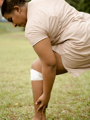 a woman wearing kneeheat while stretching on a field